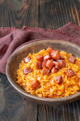 Rustic bowl of spicy tomato and chorizo risotto on wooden table