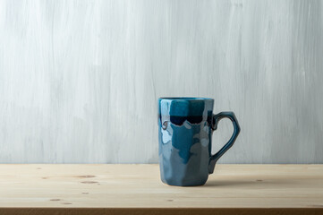 Blue mug on wooden table on grey background.