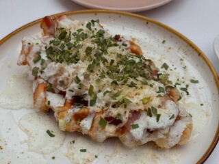 Waffle with bacon, cheese, onions and cream cheese on a plate