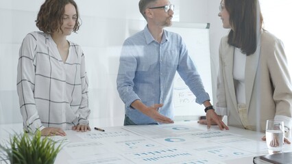 Professional colleagues reviewing financial reports, collaborating on strategic planning in contemporary workspace with collaborative atmosphere