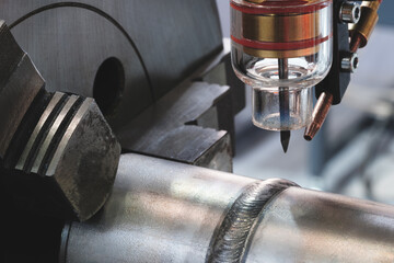 Close-up of modern industrial welding machine with fixed pipe with weld seam, industrial concept background