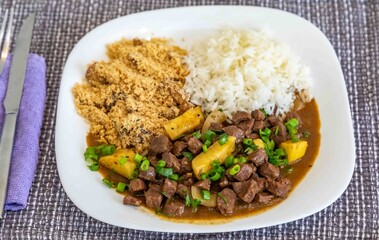 The most traditional Brazilian dish known as picadinho de carne, prepared with cubes of tender, lean beef in a stew with a sauce with typical seasoning and spices, accompanied by white rice and banana