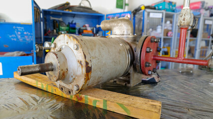 A screw pump placed on a workbench inside a maintenance workshop, awaiting inspection and repair,