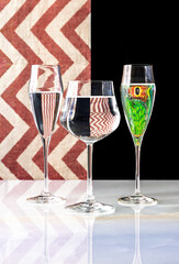 Glasses of water and reptile eyes reflected.  Red and white striped background.