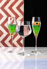 Glasses of water and reptile eyes reflected.  Red and white striped background.
