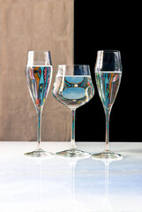 Glasses of water and colors reflected. Beige and black background.
