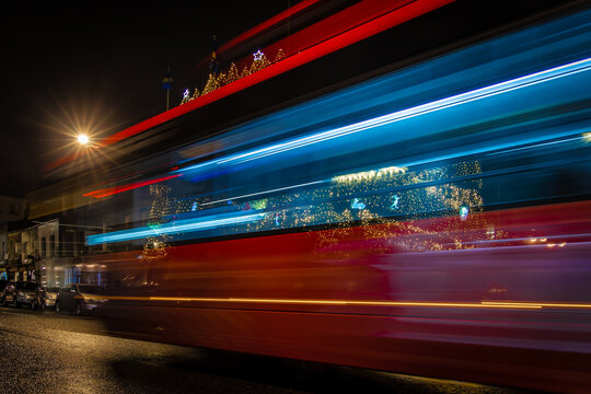 Classic London red bus navigates through a brightly lit street with Christmas decorations and busy foot traffic. Ideal for travel, holiday, or urban lifestyle themes. - Powered by Adobe