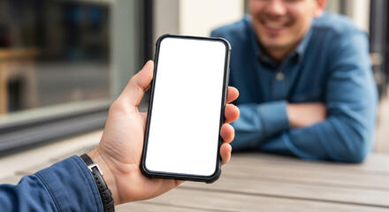 A person sitting at an outdoor cafe table with a smartphone showing a blank screen, perfect for travel blogging and mobile app presentations