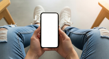 A person relaxing with their feet up, holding a smartphone with a blank white screen, perfect for leisure, mobile browsing, and app usage at home
