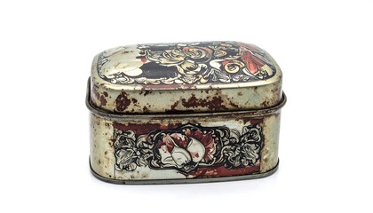 A small, rectangular metal box with an elaborate design on its top and front, showing signs of age and wear