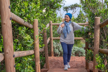 Senior caucasian woman on hiking trip with backpack on shoulders enjoying freedom and nature. Elderly active woman on a leisure trip, healthy lifestyle in retirement