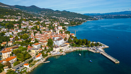 Scenic aerial view of the coastal town Lovran on the Opatija Riviera, Croatia, with red-roofed houses, Adriatic Sea, and green Učka mountain slopes in the background