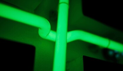 Illuminated Green Neon Tubes Sign On Black, close up view
