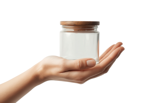 A clear glass jar with a wooden lid is cradled in a person's hand against a transparent background