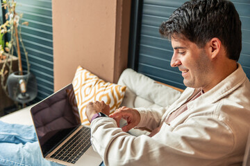 Hispanic man teleworking from home checking smartwatch