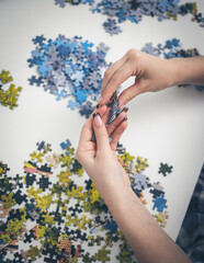 Hand Of A Little Girl Assembling A Puzzle On A Table