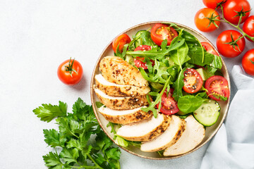Healthy food. Green salad with grilled chicken meat at white table. Top view.
