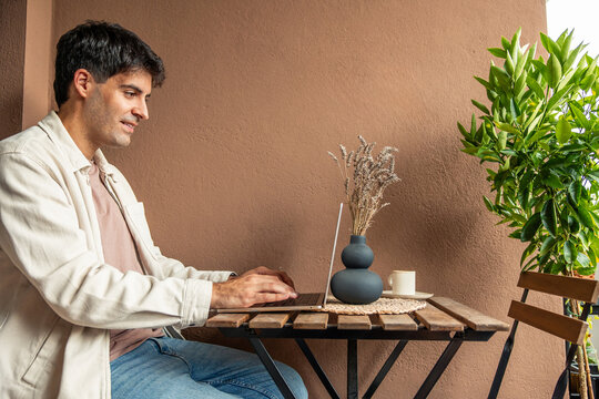 Young Hispanic man teleworking on balcony, remote work