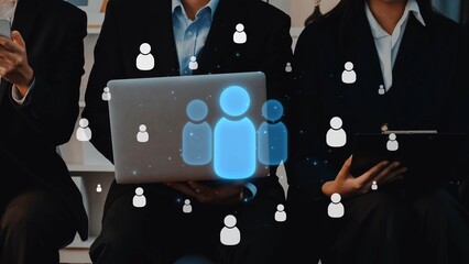 Professionals engage in networking and collaboration within a bright office setting, utilizing technology on a laptop and tablet while surrounded by digital people icons. Raster