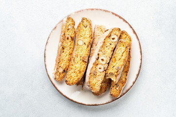 Biscotti cookies, italian bakery with nuts on white plate. Top view on white stone table.