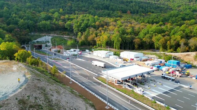 Aerial view of Učka (Ucka) Tunnel and toll booth surrounded on A8 motorway by autumn forest on the Rijeka side, showing colorful foliage and winding highway through the mountains