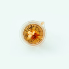 Top view of blooming flower tea in glass teapot on white background.