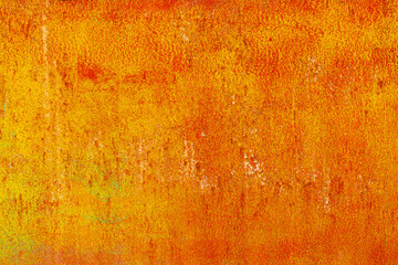 Close-up of a weathered rusty metal surface with a vibrant orange and yellow texture. The corroded iron shows peeling paint and oxidation, creating an abstract industrial background with a rough, aged
