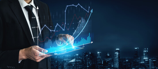 A businessman in a formal suit uses a tablet to analyze financial data, surrounded by digital...