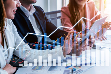 Business professionals engage in a collaborative meeting focused on analyzing financial data with digital tools and visual charts in a modern office setting. Scalp