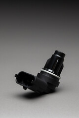 New black plastic crankshaft position sensor for an internal combustion engine on a gradient gray background