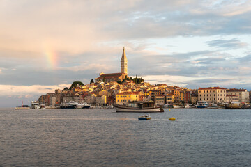 A spectacular sunrise in Rovinj, Croatia. The colorful houses of the old town are beautifully illuminated by the rising sun. A rainbow over the Adriatic resort.