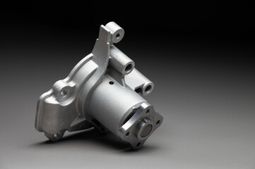 A water pump for a car's cooling system on a black gradient background. The water pump circulates coolant through the engine block. The car parts are new.
