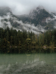 The spectacular Hintersee Alpine Lake in the German Alps at sunrise. A misty autumn morning reflects in the turquoise water. Cloud-capped mountains.