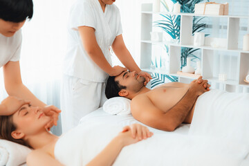 Obraz premium Caucasian couple enjoying relaxing anti-stress head massage and pampering facial beauty skin recreation leisure in dayspa modern light ambient at luxury resort or hotel spa salon. Quiescent