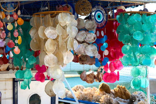 Colorful handmade shell and capiz decorations hanging at a seaside market stall, creating a vibrant display of natural and artistic crafts.