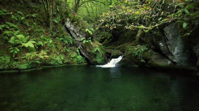 Tracking shot flying over a waterfall and a natural pool on the Infierno river, near Espinareu village, Pilona, Asturias, Spain