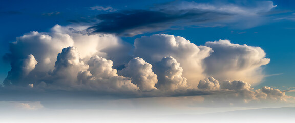 Dramatic cumulonimbus clouds towering in a vibrant blue sky during golden hour