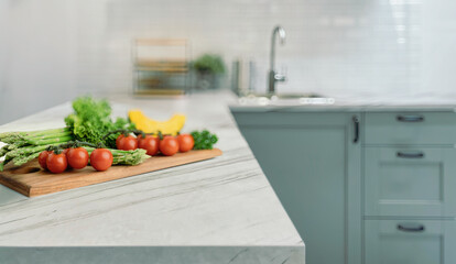 Fresh vegetables on wooden cutting board with blurred kitchen background