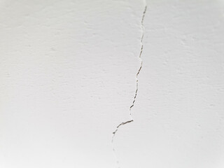 A crack in the plaster, a cracked white wall. A whitewashed wall, a damaged ceiling. A cracked white concrete wall.