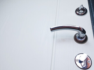 Entrance door with metal handles and locks. Close-up of a white door to an apartment, house.