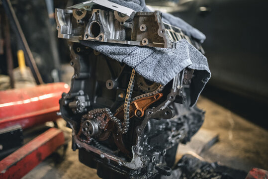 Close-up of a partially disassembled engine block, showcasing internal parts and chain. - Powered by Adobe