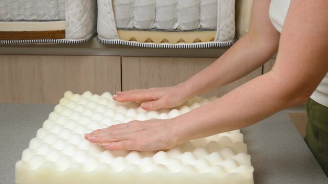 Mattress filler. A mattress sample is in the woman's hands. Independent spring blocks and fillers made of coconut coir, foam rubber, algae, cotton in a cotton cover