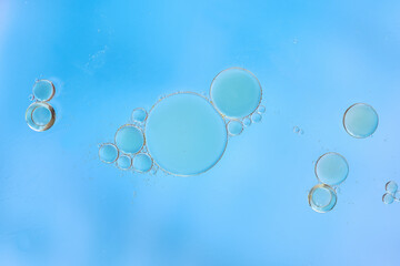 Macro shot of transparent blue bubbles of various sizes suspended in water, on a light blue background. Clean, minimalist, and airy composition, soft lighting and clear copy space. cosmetic concept.