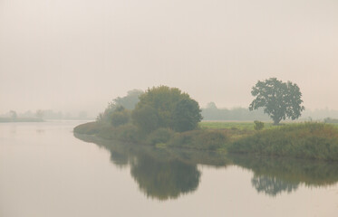 Beautiful landscape, river, trees covered with fog.