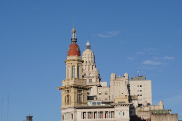 Fototapeta premium Historic towers and domes of classic architecture under a clear blue sky in the city center, showcasing ornate details and contrasting colors of old urban buildings.