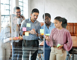 Business people meeting at office and using sticky notes on glass to share idea. Brainstorming and teamwork concept. Sticky note on glass wall.