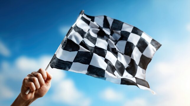 Close-up of a hand waving a black and white checkered flag vigorously against a bright, sunny sky