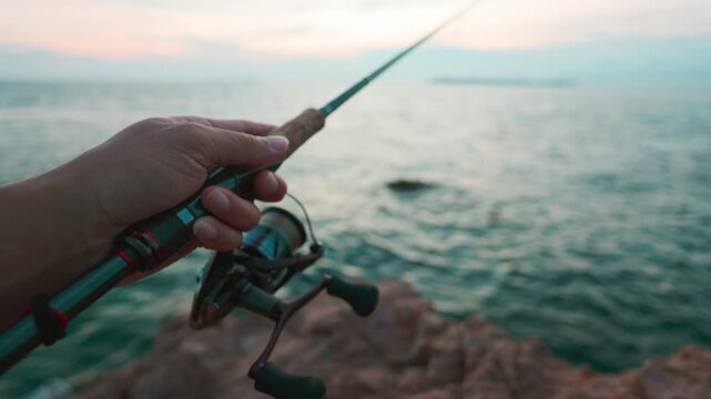 Man hand fishing reel on seashore island sea sport fishing game