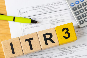Indian taxes. An Indian income tax form on a desk with a calculator and pen, and wooden blocks with the symbol ITR-3. The financial concept of India. CLose up