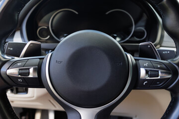 Car steering wheel with multifunction buttons and paddle shifters, modern vehicle interior